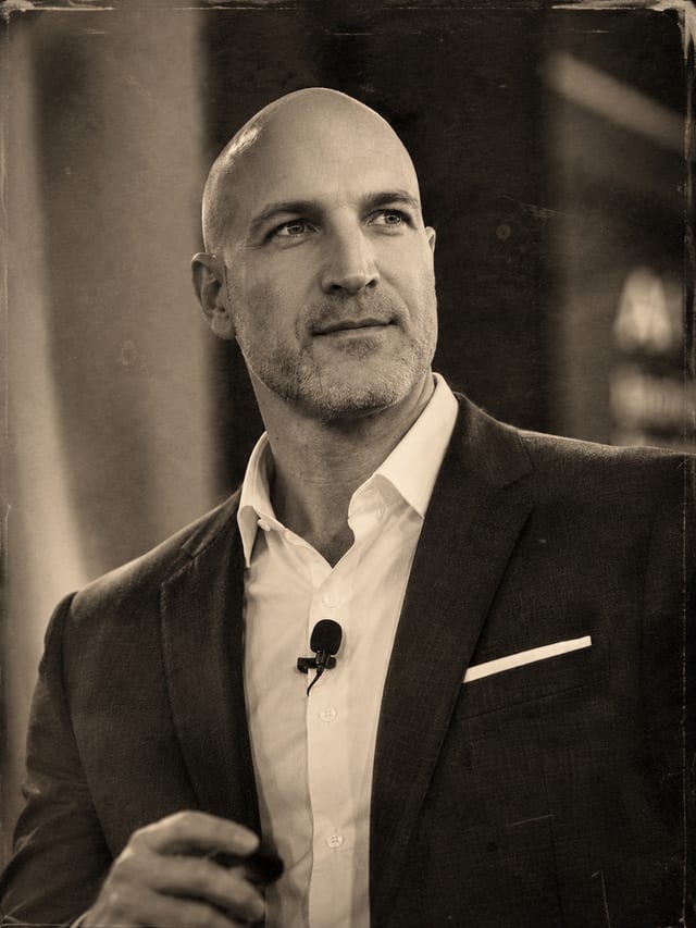 Dr. Jeff Wurfel speaking on stage, wearing a lapel microphone